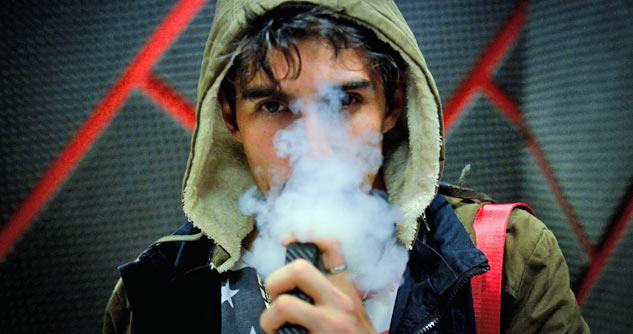 Teen boy in hoodie using vaping pen