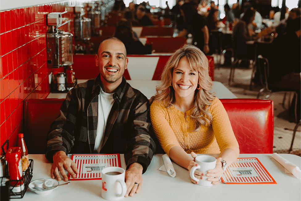 Carlos and Amy sitting next to each other at a diner