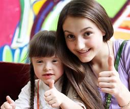 Teen with girl with down syndrome, thumbs up
