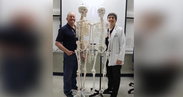 2 scientists standing next to skeletons 